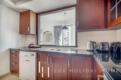 a kitchen with wooden cabinets and a white refrigerator at LUX The Fountain View Suite in Dubai
