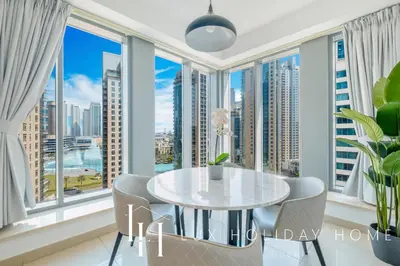 a dining room with a table and chairs and large windows at LUX The Fountain View Suite in Dubai