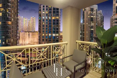 a chair on a balcony with a city skyline at LUX The Fountain View Suite in Dubai