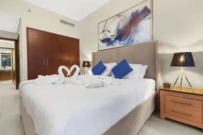 a bedroom with a large white bed with blue pillows at Chic City Apartment in Dubai Gym, Pool, and Free Parking in Dubai