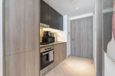 a kitchen with wooden cabinets and a stove top oven at Beautiful Pool View JVC Cozy and Stylish Czechin in Dubai