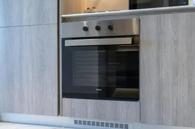 a oven in a kitchen with wooden cabinets at Beautiful Pool View JVC Cozy and Stylish Czechin in Dubai