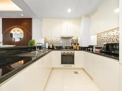 a white kitchen with white cabinets and a sink at Stunning 2BR with Burj View & Infinity Pool in Dubai