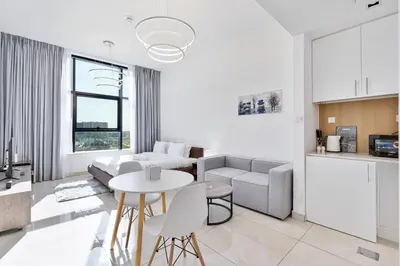 a white living room with a couch and a table at Lovely Studio with Pool and Gym in Dubai