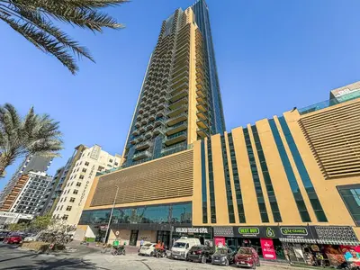 a tall building with cars parked in front of it at Lovely Studio with Pool and Gym in Dubai