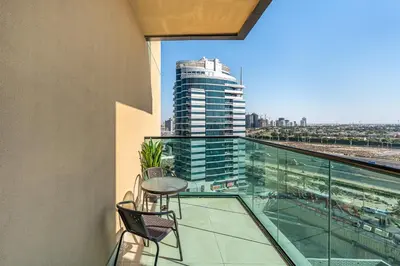 a balcony with a table and chairs on a building at Lovely Studio with Pool and Gym in Dubai