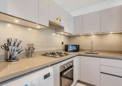 a kitchen with white cabinets and a stove top oven at Fully Furnished 2 Bed in Sobha Creek Vista Reserve, Hosted by Desert City Stays in Dubai