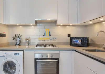 a kitchen with white cabinets and a washer and dryer at Fully Furnished 2 Bed in Sobha Creek Vista Reserve, Hosted by Desert City Stays in Dubai