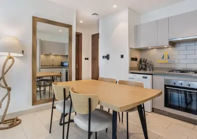 a kitchen with a wooden table and chairs and a mirror at Fully Furnished 2 Bed in Sobha Creek Vista Reserve, Hosted by Desert City Stays in Dubai