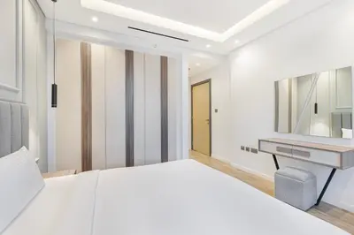 a white bedroom with a bed and a desk at Daniels 1BR at Jumeirah Garden City in Dubai