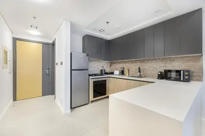 a kitchen with black cabinets and a white counter top at Daniels 1BR at Jumeirah Garden City in Dubai