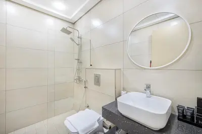 a white bathroom with a sink and a mirror at Daniels 1BR at Jumeirah Garden City in Dubai