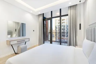 a bedroom with a bed and a desk and a window at Daniels 1BR at Jumeirah Garden City in Dubai