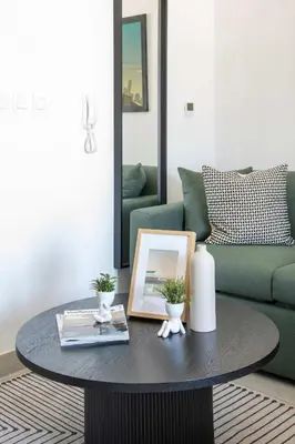 a coffee table in a living room with a green couch at Frank Porter - Bella Rose in Dubai