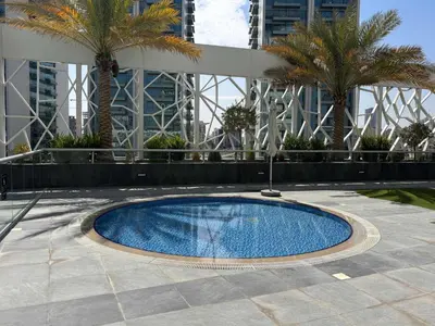 a swimming pool in a courtyard with palm trees and buildings at Frank Porter - Bella Rose in Dubai
