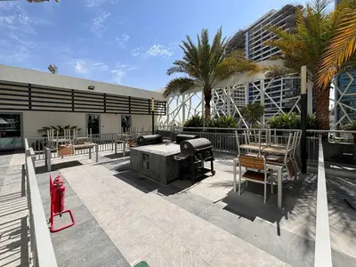 a patio with a grill and chairs and a building at Frank Porter - Bella Rose in Dubai