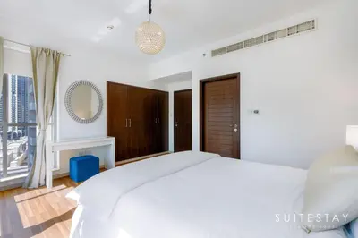 a white bedroom with a large bed and a window at One Bed with Burj Khalifa View in Dubai