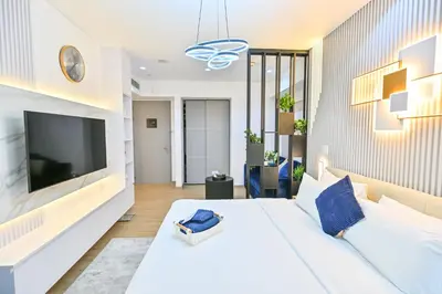 a bedroom with a large white bed and a flat screen tv at Upgraded Luxury Studio Apartment - Marina View - 5-Star Hotel Amenities in Dubai