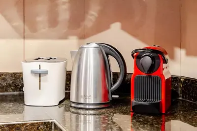 a red and blackffeepot sitting on a kitchen counter at 804 Yansoon 5 Amazing 1BR Apt Downtown Dubai in Dubai