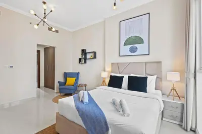 a bedroom with a large white bed and a blue chair at Premium 1 bedroom Apartment near Dubai Mall in Dubai