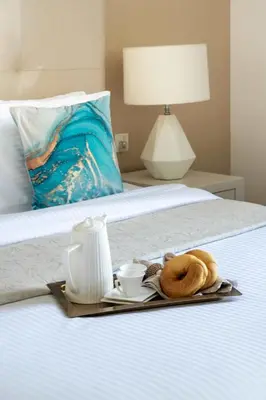 a tray with two donuts and cups on a bed at Frank Porter - Damac Cour Jardin in Dubai