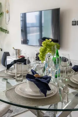 a glass table with plates and a vase of grapes at Frank Porter - Marina Vista Tower 2 in Dubai