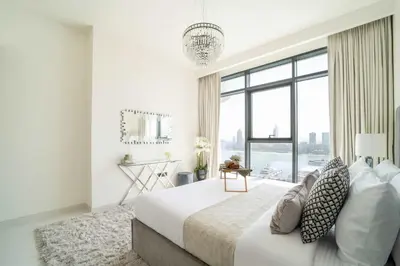 a white bedroom with a large bed with a large window at Frank Porter - Marina Vista Tower 2 in Dubai