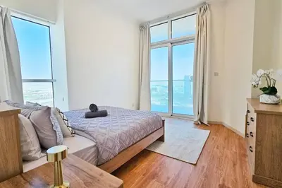 a bedroom with a bed and large windows at Luxury 2BR Carson Tower B Apt in Dubai