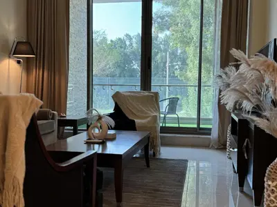 a living room with a table and a large window at Dubai Apartment in Meydan in Dubai