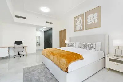 a white bedroom with a large bed and a desk at Lux BnB I Executive Tower I Ocean View in Dubai