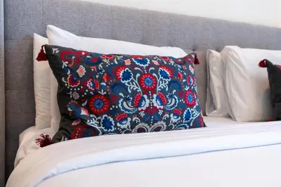 a bed with a red and blue pillow on it at Lux BnB I Executive Tower I Ocean View in Dubai