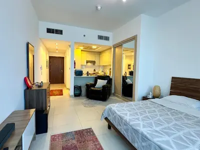a bedroom with a bed and a living room at Cozy Studio in JVC in Dubai