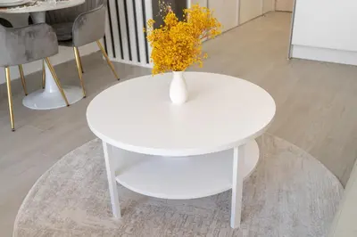 a white table with a vase with yellow flowers on it at Bright & Airy Studio in JVC in Dubai