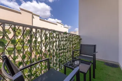 a balcony with a fence with a chair and a table at Bright & Airy Studio in JVC in Dubai
