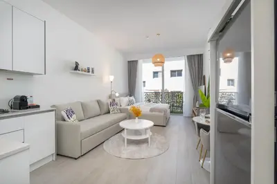 a white living room with a couch and a table at Bright & Airy Studio in JVC in Dubai