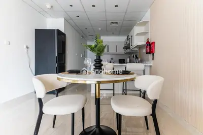 a dining room with a table and white chairs at Newly Furnished Unit in Elite, Business Bay in Dubai