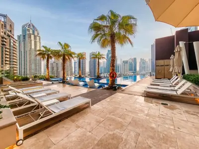 a rooftop pool with chaise lounge chairs and palm trees at Brand new 1 bedroom in Marina gate 2, Dubai Marina in Dubai