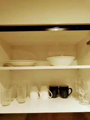 a shelf with bowls and plates and glasses on it at Luxury 1BR Majestine Apartment in Dubai