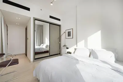 a white bedroom with a large bed and a mirror at 2035-Inspired 1BR - JVC Dubai Near Burj Khalifa in Dubai