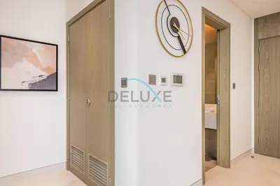 a hallway with a door and a clock on the wall at Stunning 1BR Apartment in District One Phase III, Mohammed Bin Rashid by Deluxe Holiday Homes Al Maktoum City in Dubai