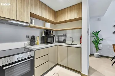 a kitchen with white countertops and wooden cabinets at bnbmehomes - Urban Oasis by Missoni in Dubai