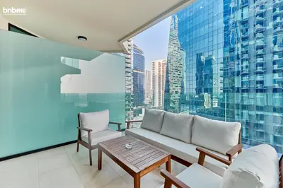 a balcony with a couch and chairs and a large window at bnbmehomes - Urban Oasis by Missoni in Dubai