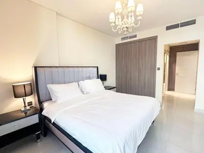 a bedroom with a large white bed with a chandelier at Stunning 1-Bedroom in The Polo Residence, Meydan in Dubai