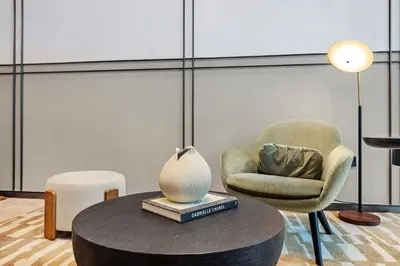 a room with a chair and a table with a lamp at FIRST CLASS 1BR Heart of Tranquility in Dubai
