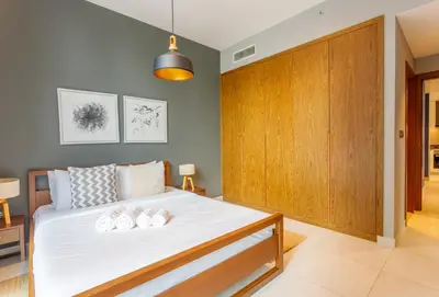 a bedroom with a large bed with a wooden closet at Stunning Marina Waterfront 2 Bed Escape in Dubai