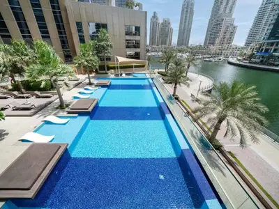 a swimming pool with chaise lounges and a body of water at Stunning Marina Waterfront 2 Bed Escape in Dubai