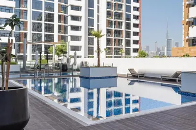 a building with a pool with palm trees on it at Trendy Azizi Riviera 1-Bed with Balcony Views in Dubai