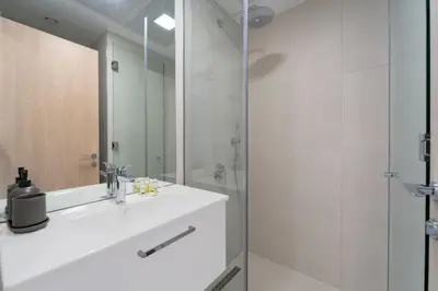 a white bathroom with a sink and a shower at Art of Modern Illumination in Dubai