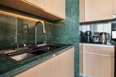 a kitchen with a stainless steel sink and green walls at Waterfront Apartment at Dubai Creek Harbour - By DuStay in Dubai