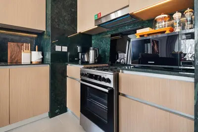 a kitchen with a stove and a microwave at Dubai Creek Poolside view Apartment - By DuStay in Dubai